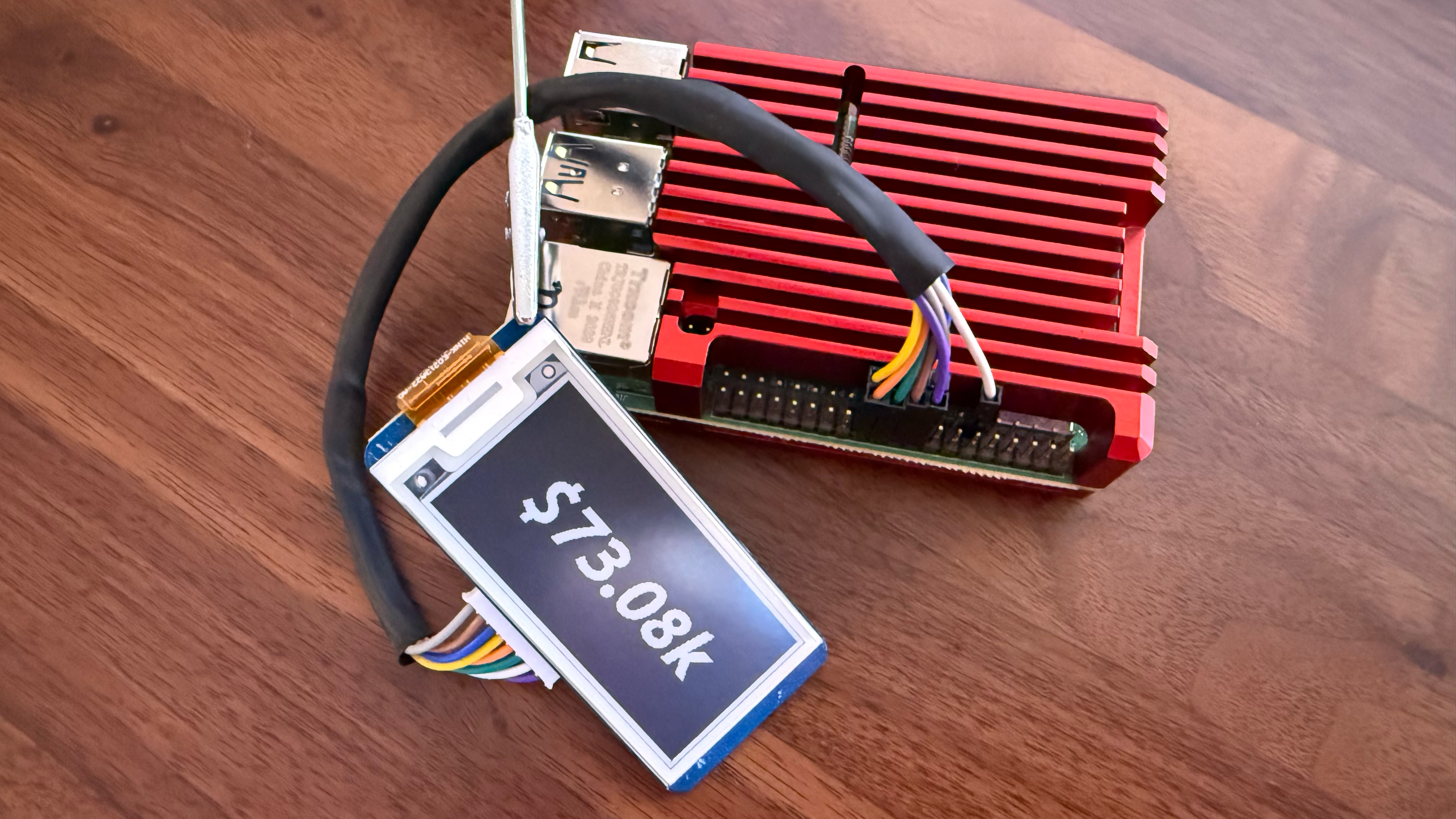 Raspberry Pi 4 in red aluminum case with Waveshare e-ink display showing $73.08k